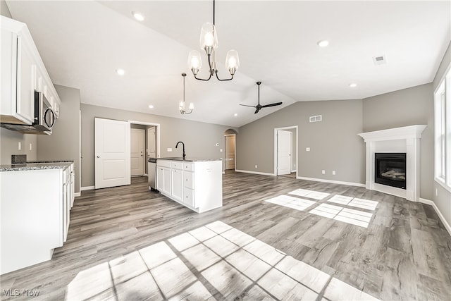 kitchen with light hardwood / wood-style flooring, lofted ceiling, ceiling fan with notable chandelier, and white cabinets