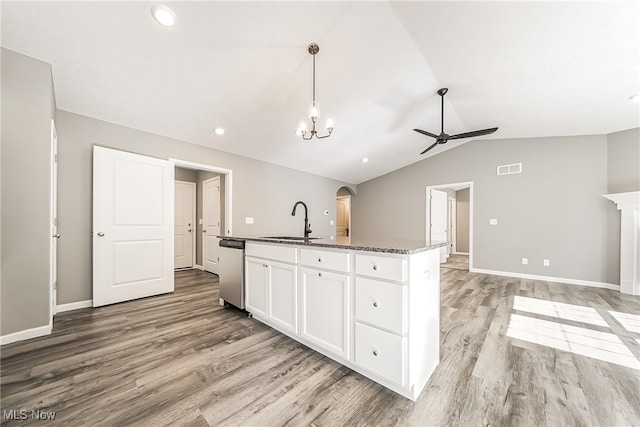 kitchen with an island with sink, white cabinetry, stainless steel dishwasher, vaulted ceiling, and sink