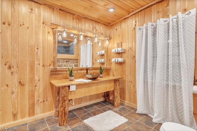 bathroom featuring tile flooring, wooden walls, toilet, wood ceiling, and vanity