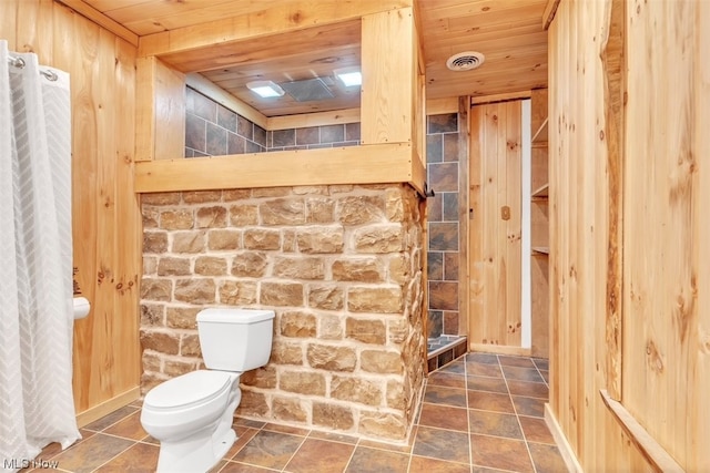 bathroom with wood ceiling, tile flooring, wood walls, and toilet