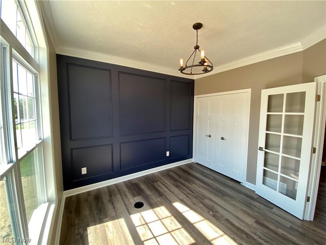 unfurnished dining area featuring dark hardwood / wood-style flooring, ornamental molding, and an inviting chandelier