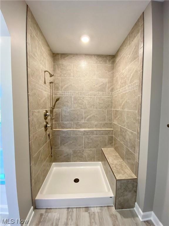 bathroom with a tile shower and hardwood / wood-style floors