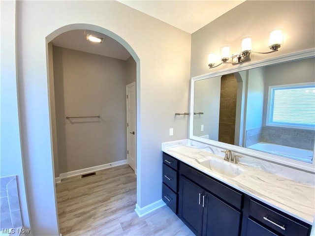 bathroom featuring hardwood / wood-style flooring, vanity, and a bath