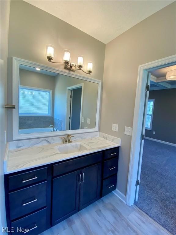 bathroom with a garden tub, vanity, and baseboards