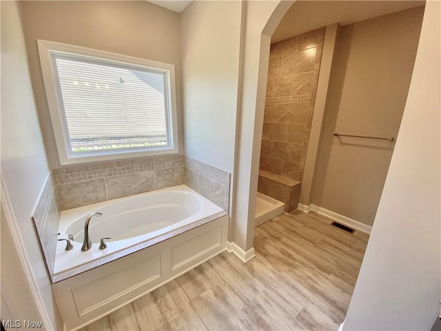 bathroom with independent shower and bath and hardwood / wood-style floors