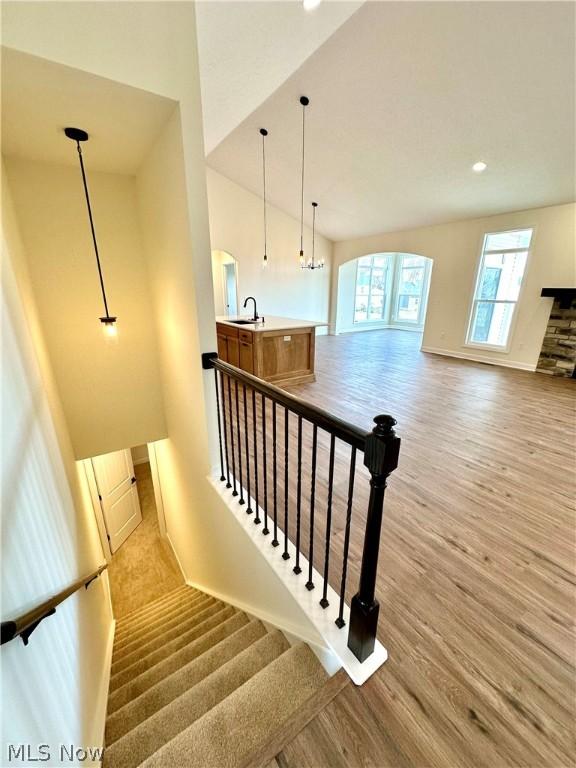 staircase with hardwood / wood-style flooring, lofted ceiling, and sink