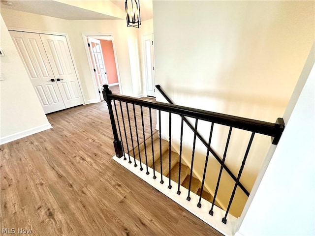 hall featuring an upstairs landing, an inviting chandelier, baseboards, and wood finished floors