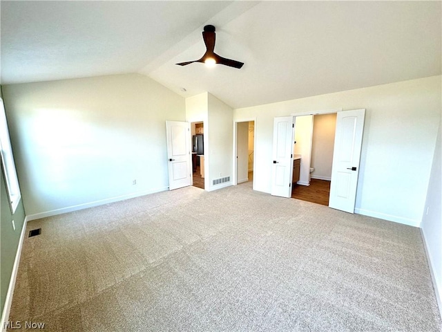 unfurnished bedroom featuring lofted ceiling, connected bathroom, carpet, and ceiling fan