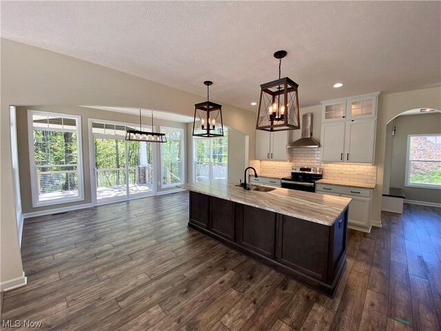 kitchen featuring wall chimney range hood, sink, white cabinets, decorative light fixtures, and stainless steel electric stove