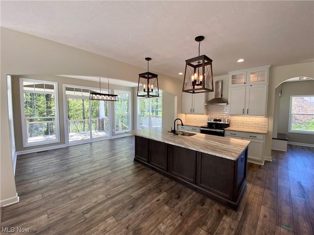 kitchen with glass insert cabinets, electric range, white cabinetry, wall chimney range hood, and decorative light fixtures