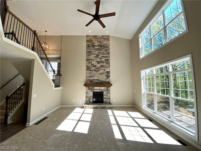 unfurnished living room featuring high vaulted ceiling, carpet floors, a fireplace, baseboards, and stairs