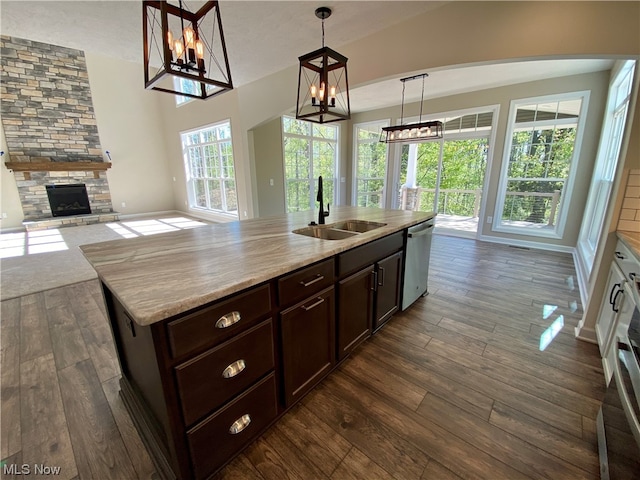 kitchen with a fireplace, decorative light fixtures, sink, dark hardwood / wood-style flooring, and stainless steel dishwasher