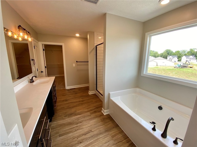 bathroom featuring vanity, separate shower and tub, wood-type flooring, and a textured ceiling