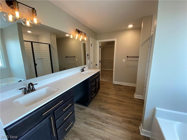 bathroom featuring a garden tub, wood finished floors, a sink, a shower stall, and double vanity