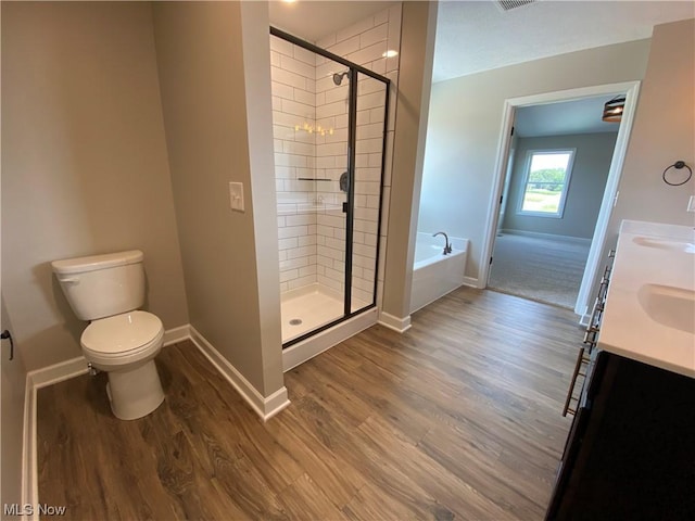 bathroom featuring a garden tub, a shower stall, baseboards, and wood finished floors