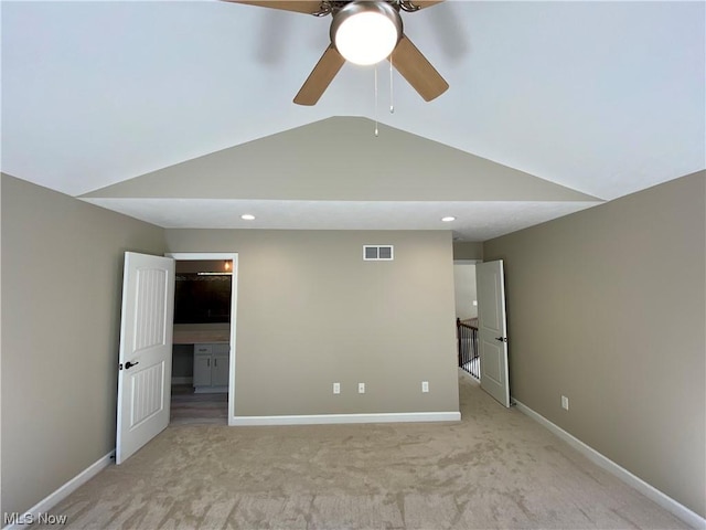 unfurnished bedroom with lofted ceiling, baseboards, visible vents, and light colored carpet