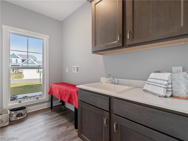 laundry room with dark wood-type flooring, a sink, cabinet space, and baseboards