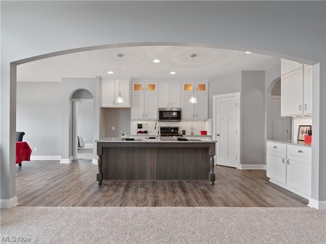 kitchen featuring glass insert cabinets, pendant lighting, stainless steel microwave, and white cabinets