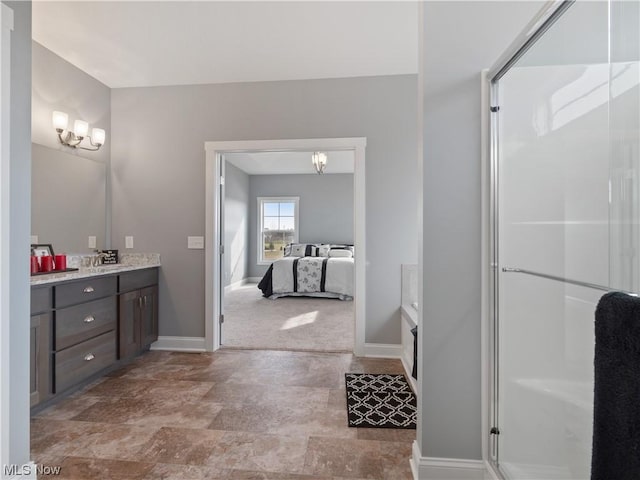 ensuite bathroom featuring baseboards, a shower with shower door, ensuite bathroom, vanity, and a chandelier