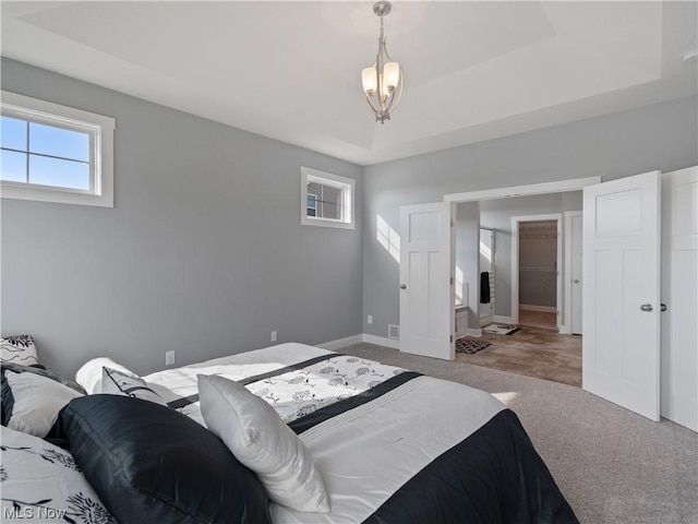 bedroom with a tray ceiling, carpet, and baseboards