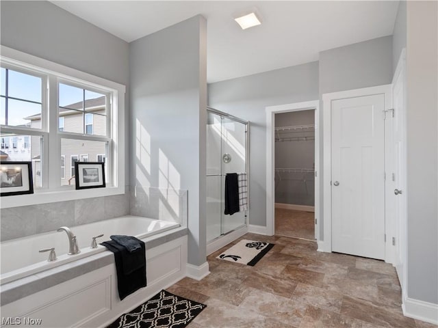 bathroom featuring a closet, a stall shower, a garden tub, and baseboards