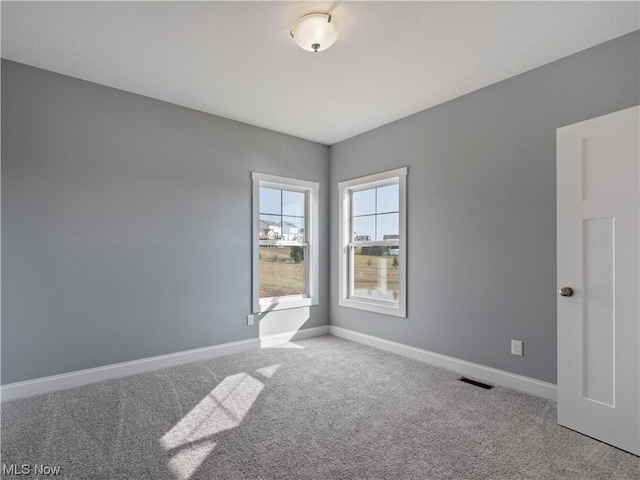 carpeted spare room featuring baseboards and visible vents