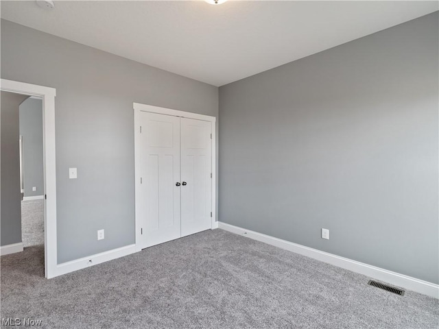 unfurnished bedroom with a closet, carpet flooring, visible vents, and baseboards