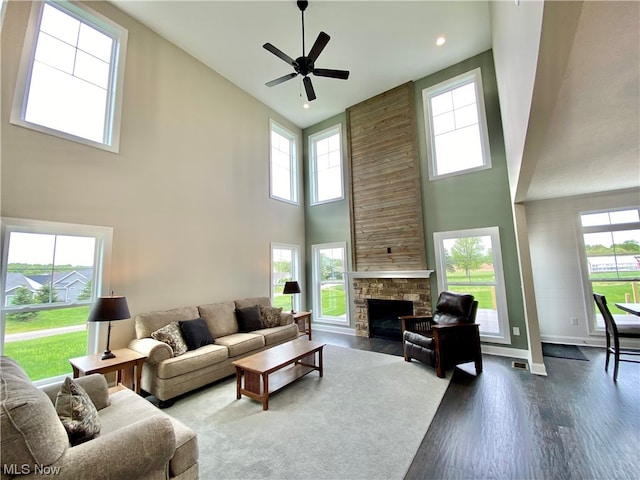 living room featuring a fireplace, ceiling fan, hardwood / wood-style floors, and a high ceiling