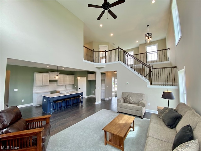 living room featuring hardwood / wood-style flooring, a high ceiling, sink, and ceiling fan