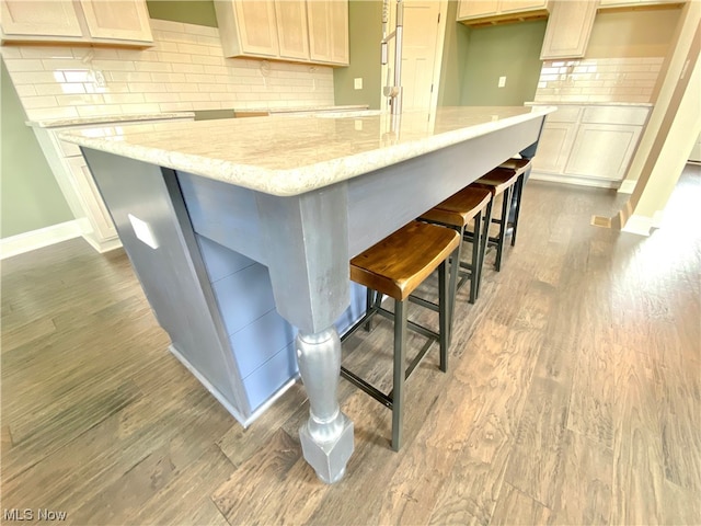 kitchen with light stone countertops, dark hardwood / wood-style floors, and backsplash