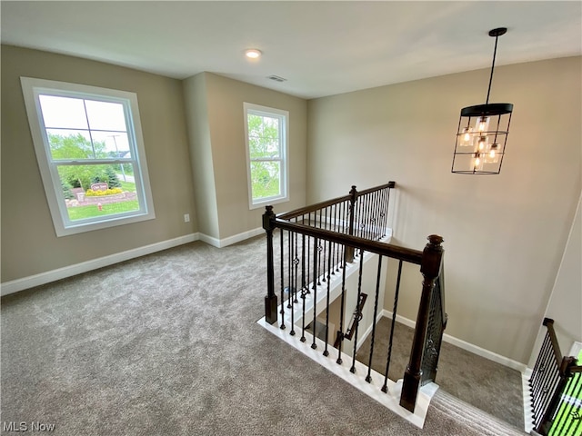 stairs with carpet flooring and a notable chandelier