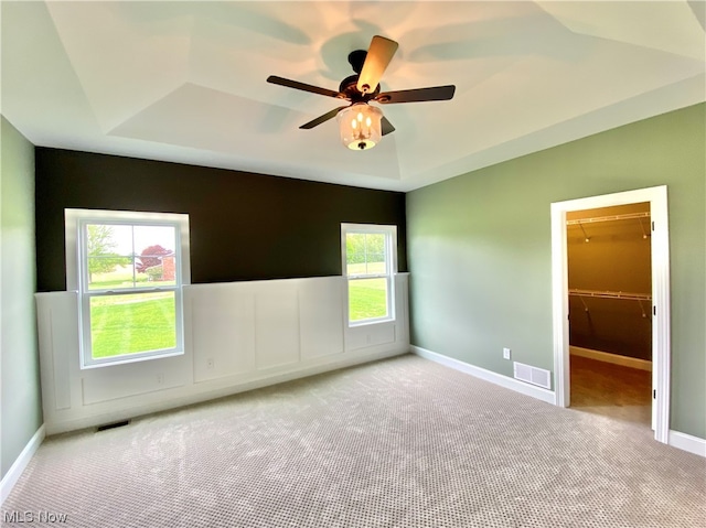 carpeted empty room with ceiling fan and a tray ceiling