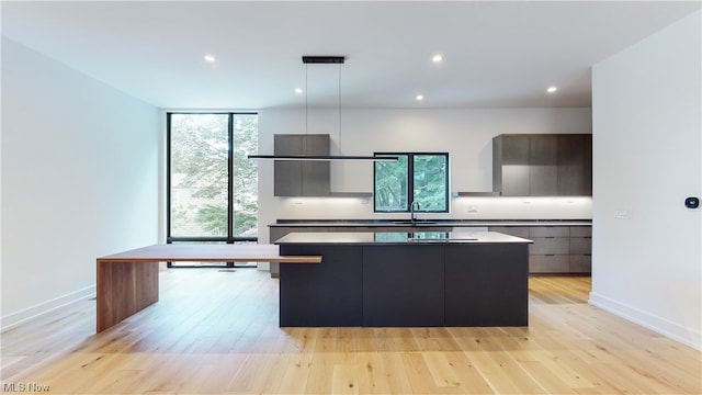 kitchen featuring a kitchen bar, sink, light wood-type flooring, a center island, and hanging light fixtures