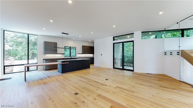 kitchen featuring pendant lighting, light wood-type flooring, a kitchen island, and a wealth of natural light