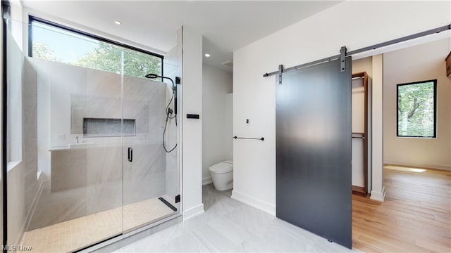 bathroom featuring tile flooring, toilet, a shower with shower door, and a healthy amount of sunlight