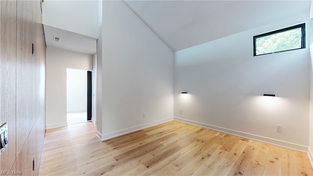 spare room featuring lofted ceiling and light hardwood / wood-style floors