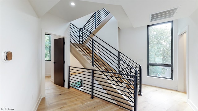 staircase featuring a healthy amount of sunlight and light hardwood / wood-style flooring