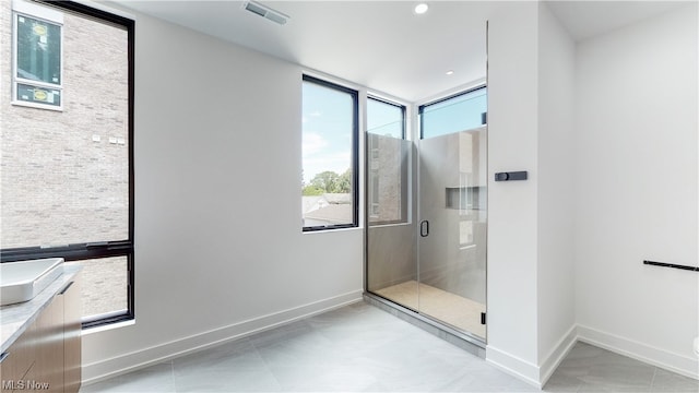 bathroom featuring a healthy amount of sunlight, tile flooring, and an enclosed shower