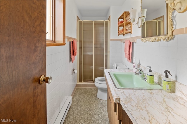 bathroom with vanity, a shower with shower door, tile walls, toilet, and baseboard heating