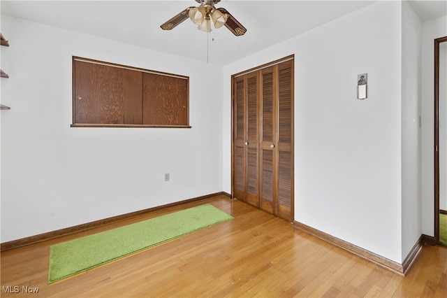 unfurnished bedroom featuring light hardwood / wood-style flooring, golf simulator, ceiling fan, and a closet