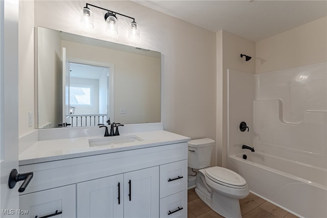 full bathroom featuring toilet, hardwood / wood-style floors, vanity, a textured ceiling, and shower / bath combination