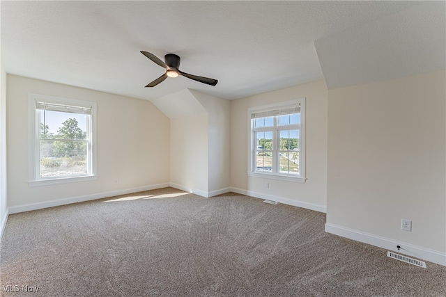 carpeted empty room featuring vaulted ceiling, a textured ceiling, and ceiling fan