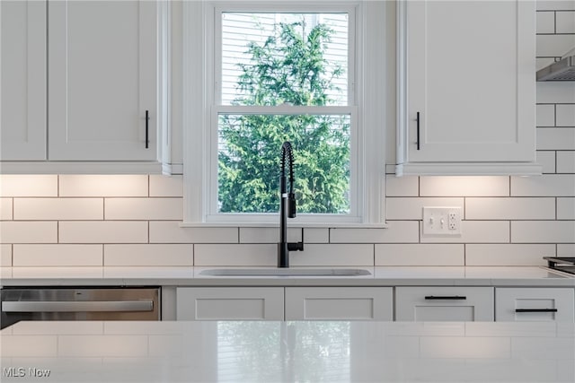 kitchen featuring dishwasher, sink, white cabinets, and decorative backsplash