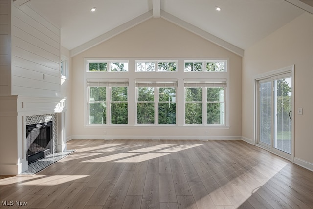 unfurnished living room featuring a fireplace, high vaulted ceiling, plenty of natural light, and light hardwood / wood-style flooring