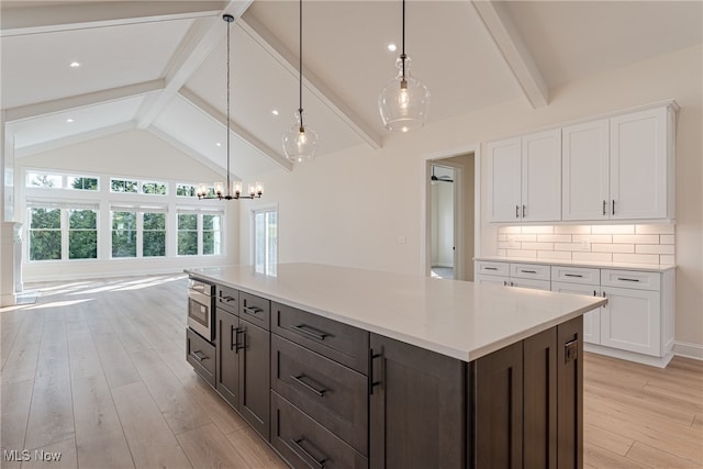 kitchen featuring white cabinetry, backsplash, a kitchen island, vaulted ceiling with beams, and light hardwood / wood-style floors