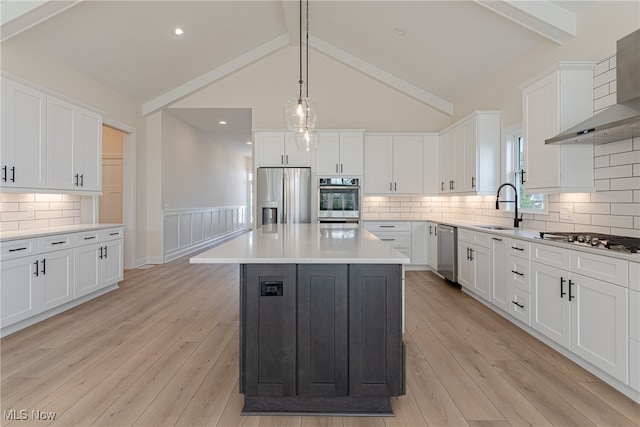 kitchen with a center island, lofted ceiling with beams, light hardwood / wood-style flooring, stainless steel appliances, and wall chimney exhaust hood