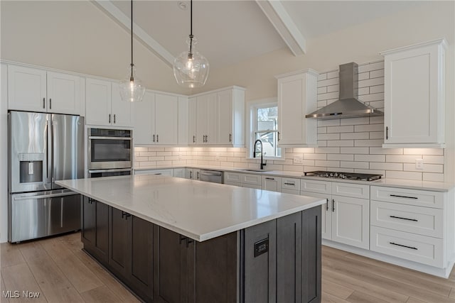 kitchen with a center island, stainless steel appliances, white cabinetry, sink, and wall chimney range hood