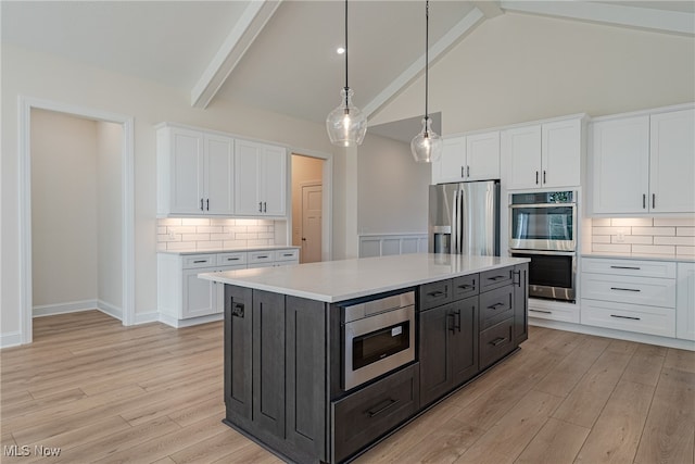 kitchen featuring stainless steel appliances, a kitchen island, beam ceiling, white cabinets, and light hardwood / wood-style floors