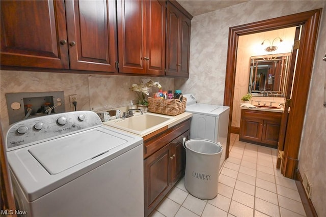 clothes washing area with washing machine and dryer, sink, light tile patterned floors, and cabinets