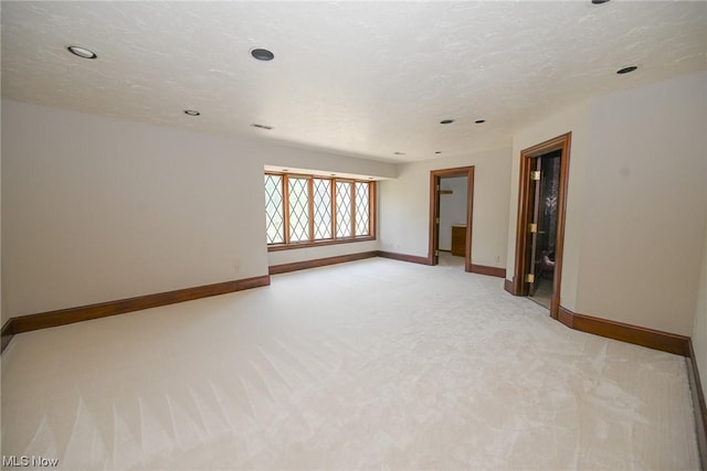 empty room with a textured ceiling and light carpet